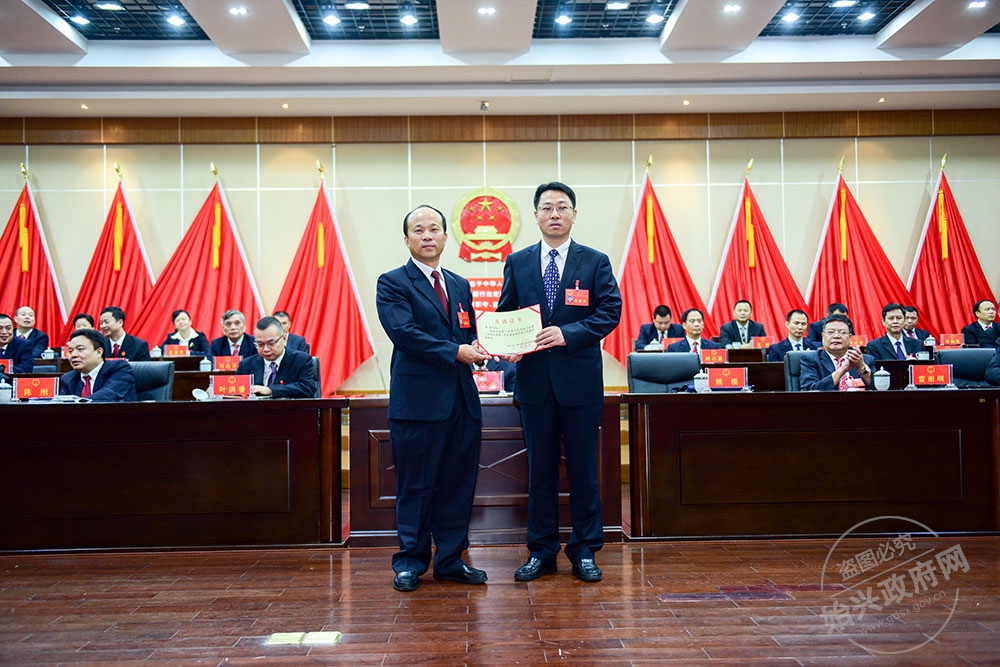 李勇當(dāng)選為始興縣人民政府副縣長(zhǎng)，，圖為賴根為李勇右）頒發(fā)當(dāng)選證書