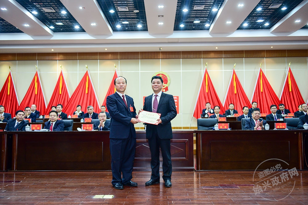何武強(qiáng)當(dāng)選為始興縣人民政府副縣長(zhǎng)，，圖為賴根為何武強(qiáng)（右）頒發(fā)當(dāng)選證書